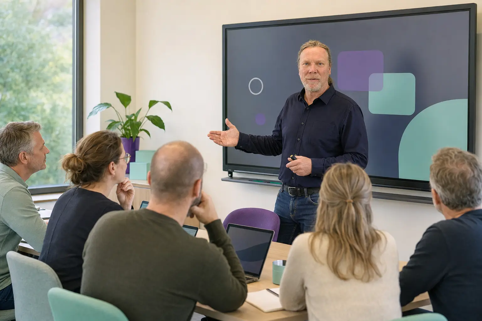 Frank Brama geeft training aan een groep deelnemers in een modern leslokaal